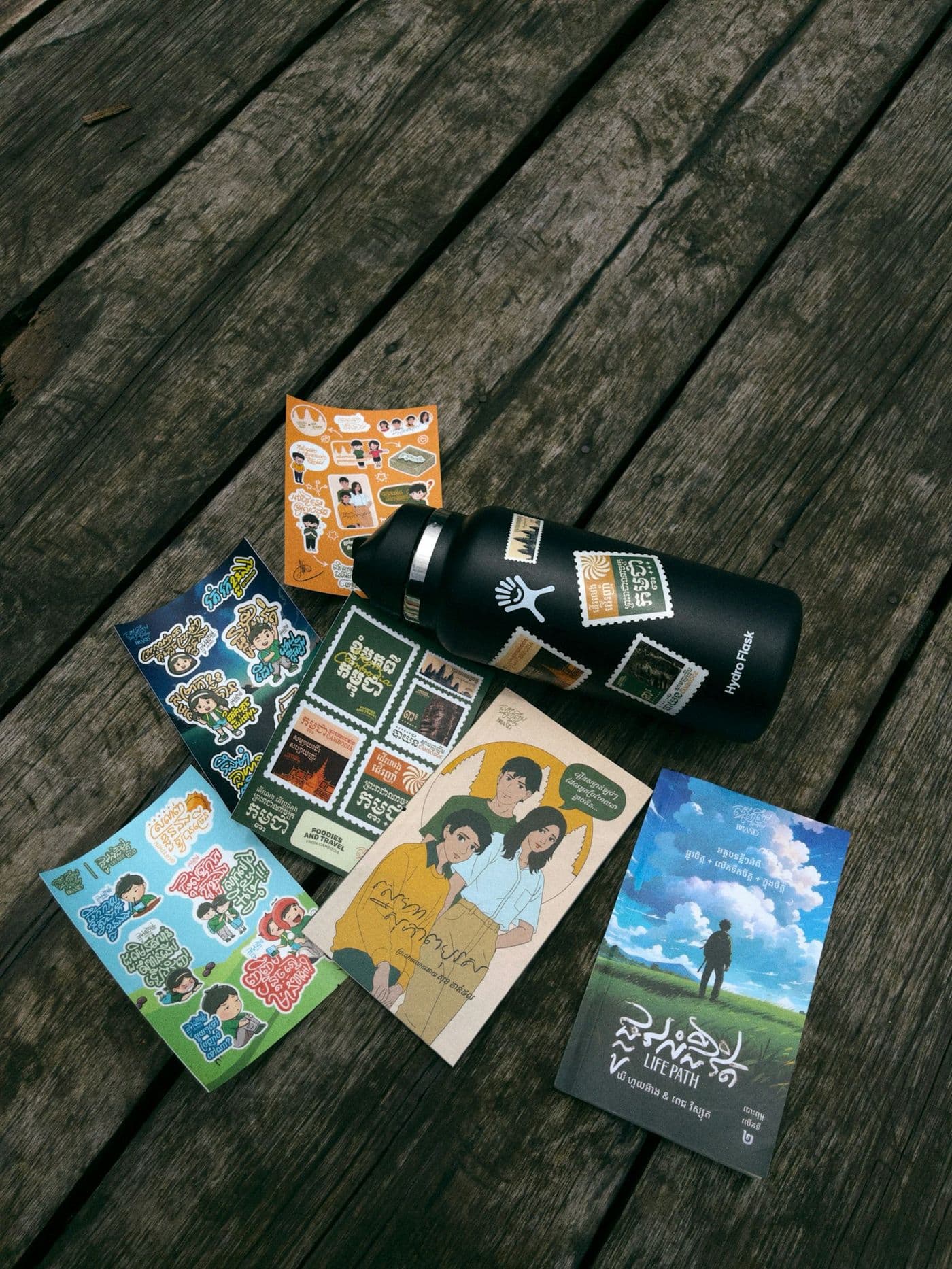 Vinyl sticker sheets beside a stickered stainless water bottle
