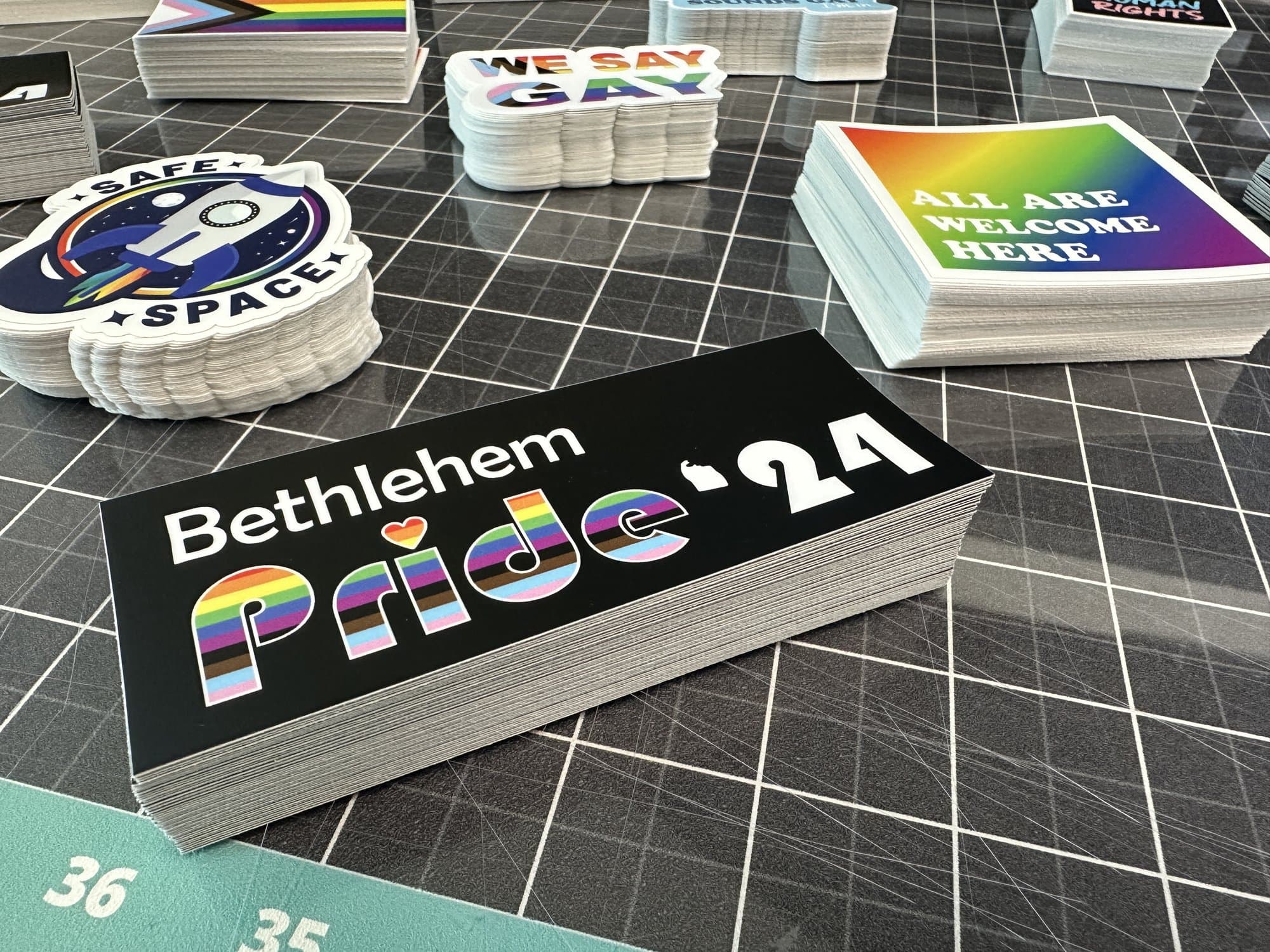 Stacks of Bethlehem Pride '24 bumper stickers beside Safe Space and All Are Welcome Here stickers