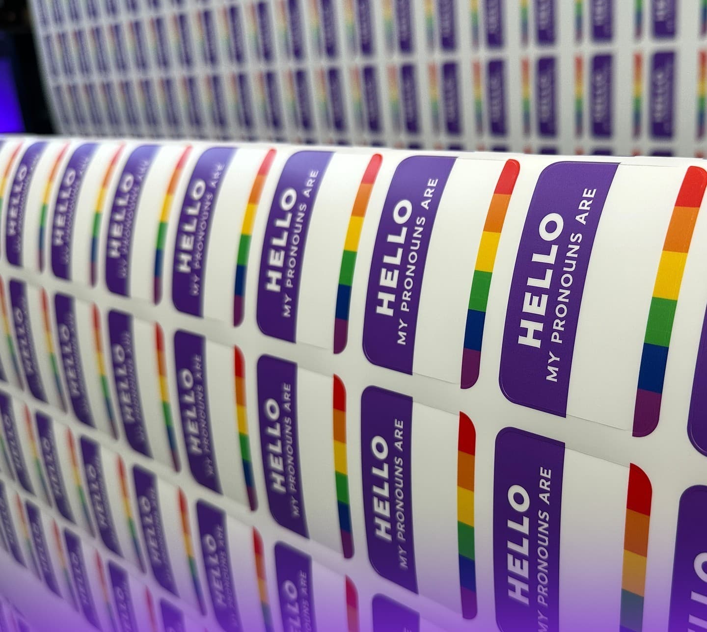 Rows of 'Hello, my pronouns are' stickers off the printer