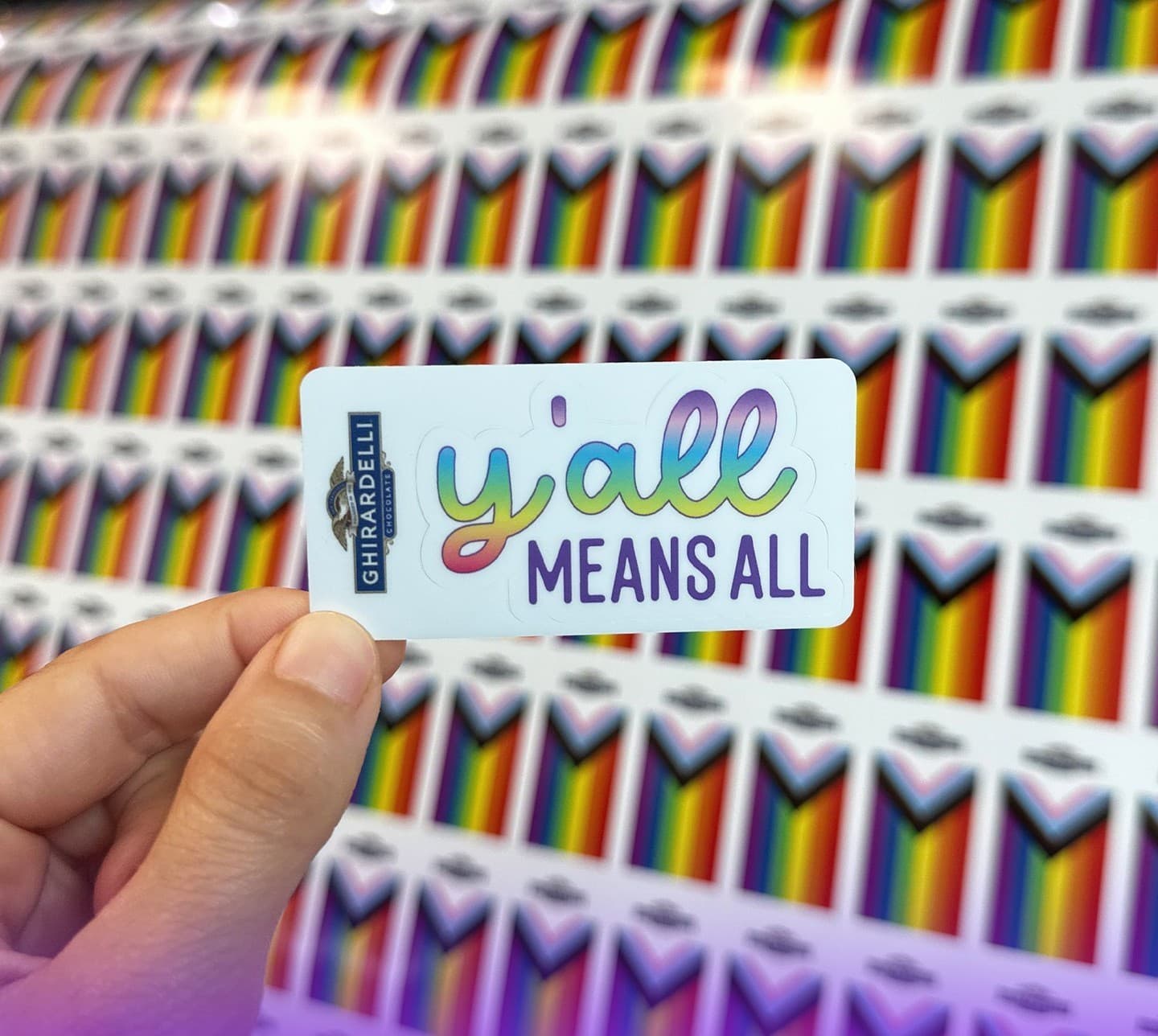 Holding a Ghirardelli 'y'all means all' sticker over progress flag sheets