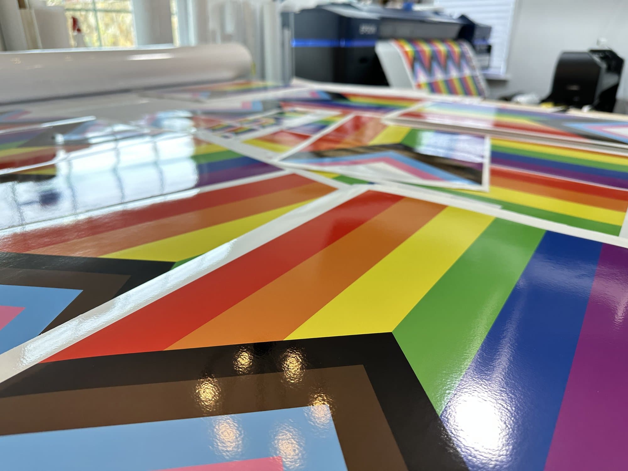 Large format progress Pride flag prints laid out in the studio