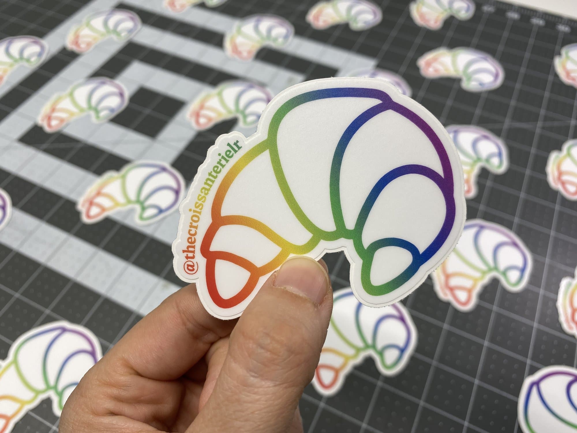 A rainbow outline croissant die cut sticker made for a bakery