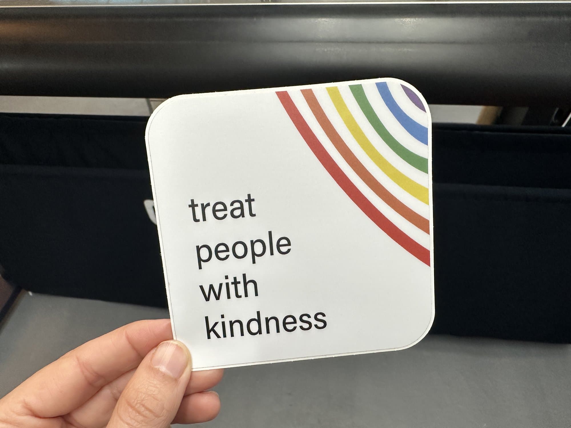 A 'treat people with kindness' sticker with rainbow arcs